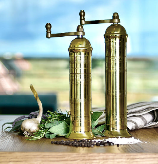 brass salt and pepper grinders on table with spices and garlic | La Maison Baude