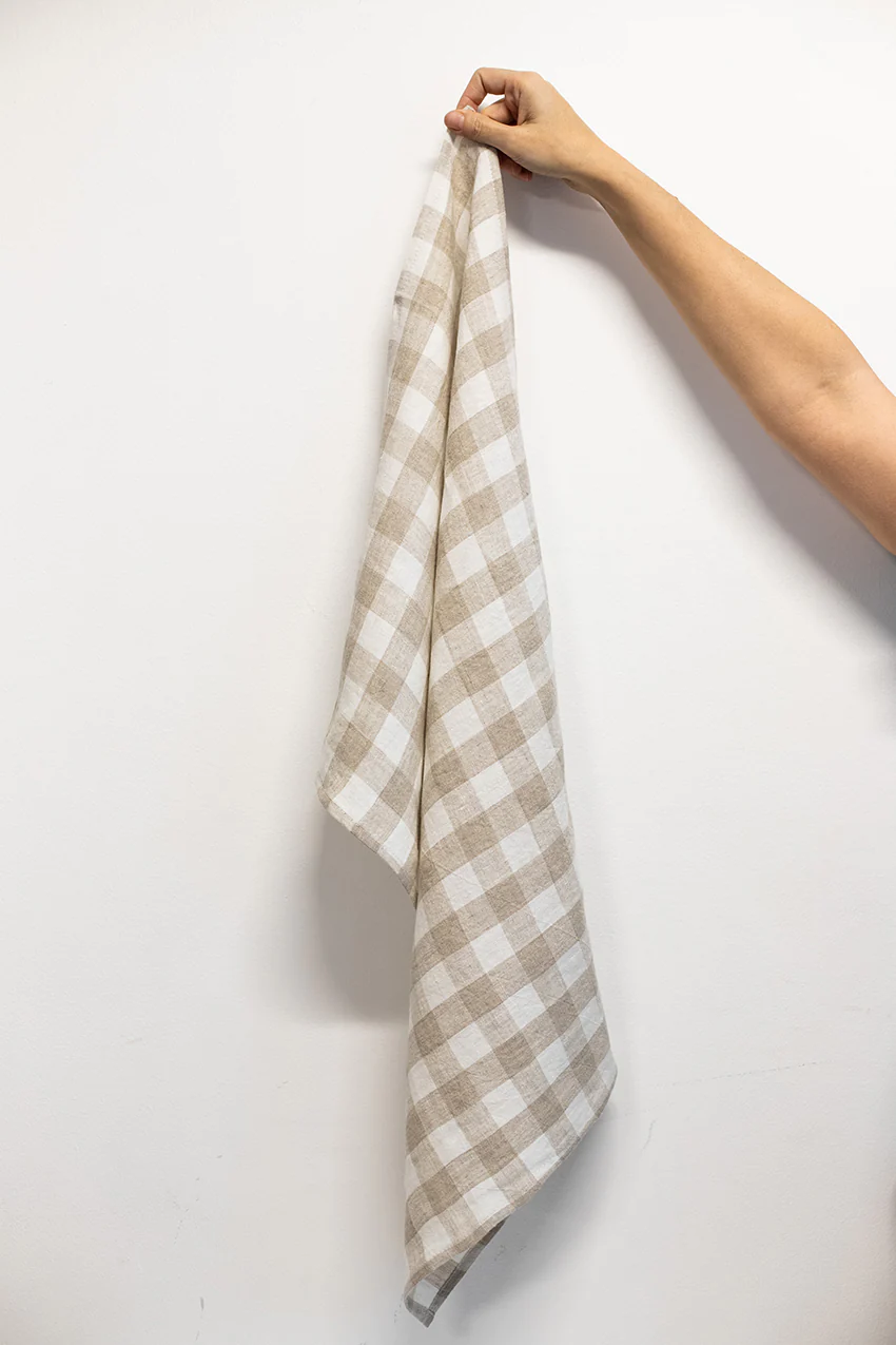 Hand holding an ivory check linen kitchen towel from La Maison Baude