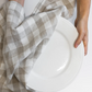 Hands drying a plate with ivory checkered kitchen towel from La Maison Baude