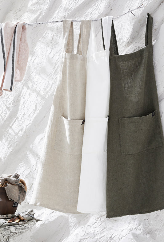 Three cross-back linen aprons hanging from a clothing line