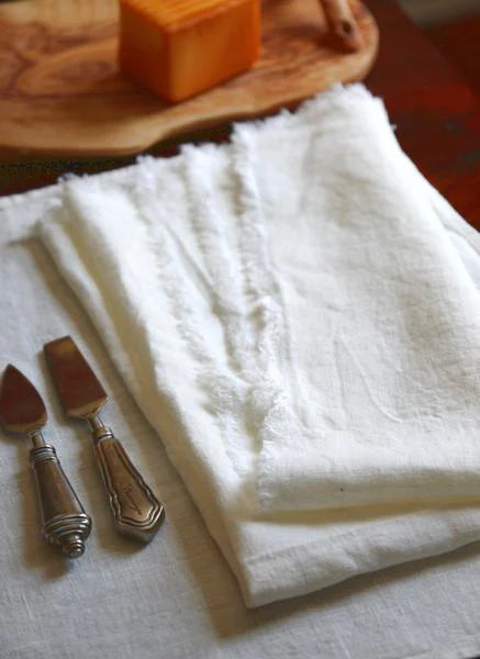 White linen napkins with fringe on table with cutlery